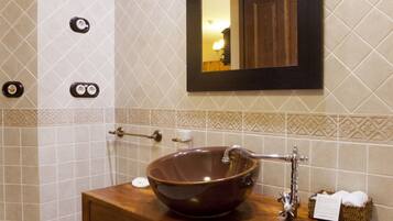 A bathroom with a wooden vanity, a large vessel sink, a towel rack, and a mirror.