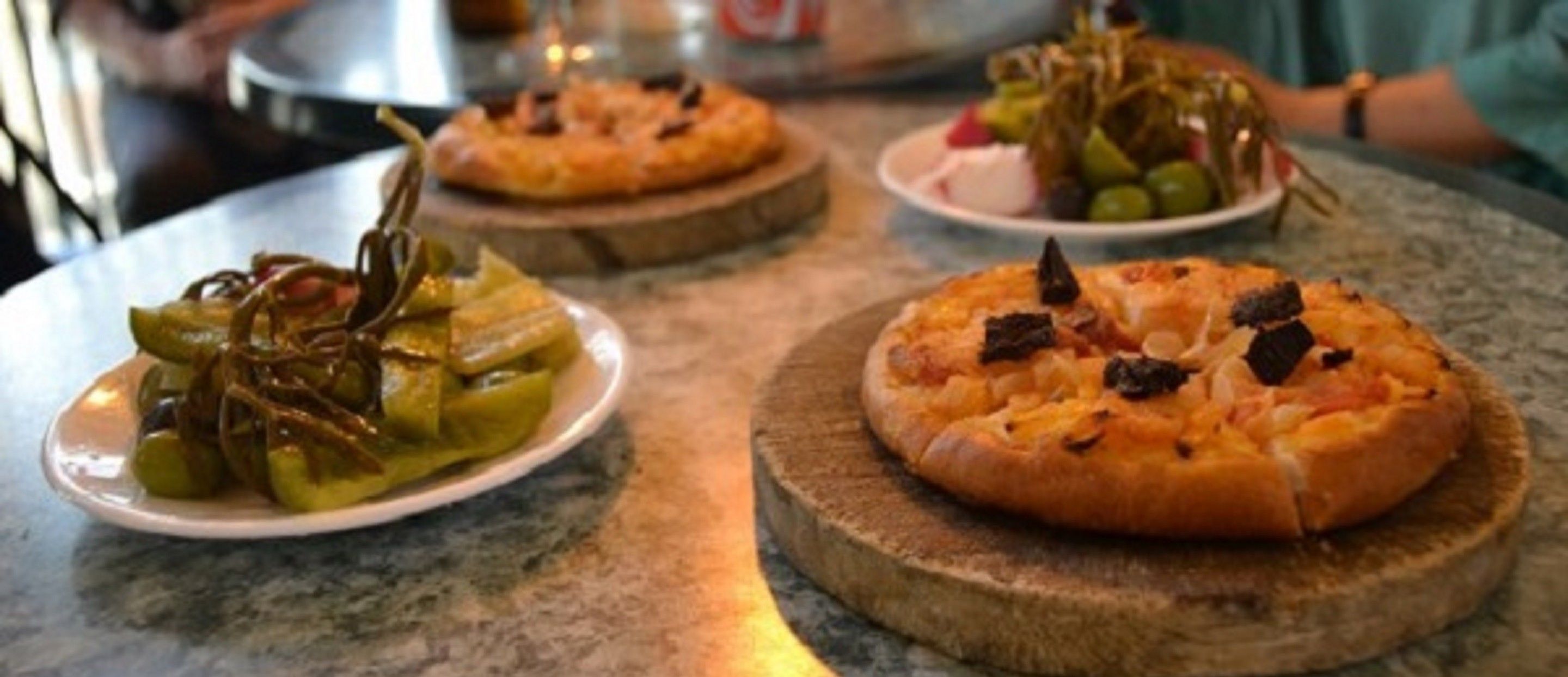 Drie pizza's op houten planken op een tafel.