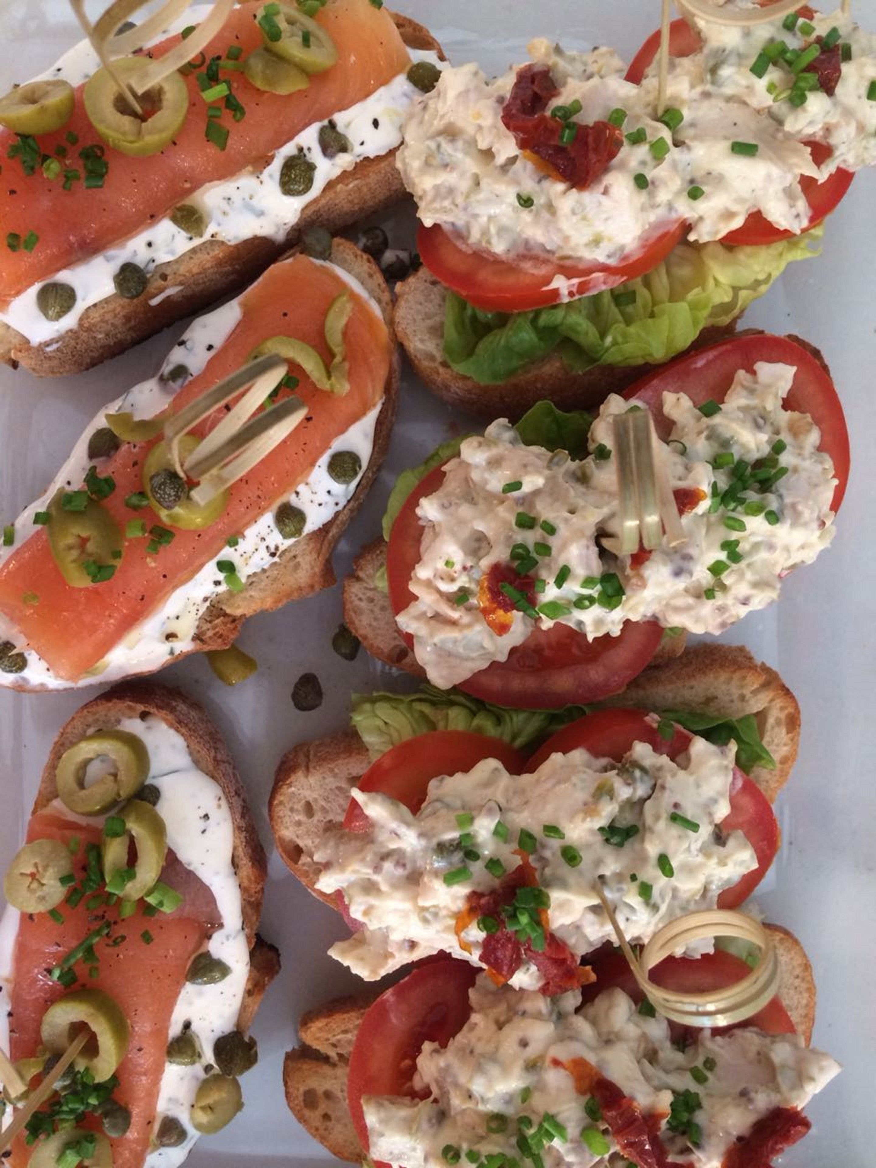 Diversos aperitivos que incluyen salmón ahumado, cremas de queso y adornos sobre pan.