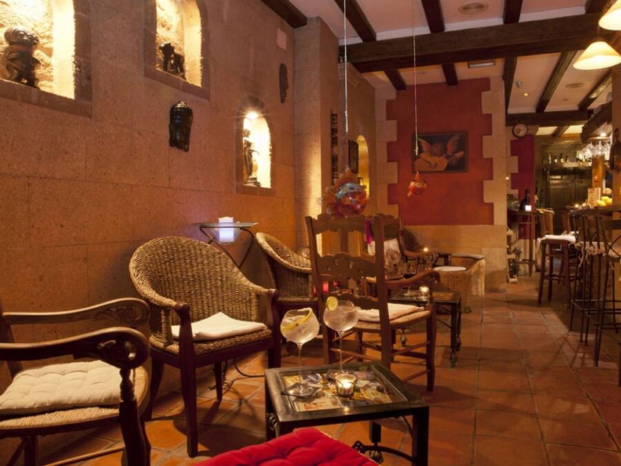 A cozy interior with wicker chairs, a glass table with magazines, and a warm stone wall.