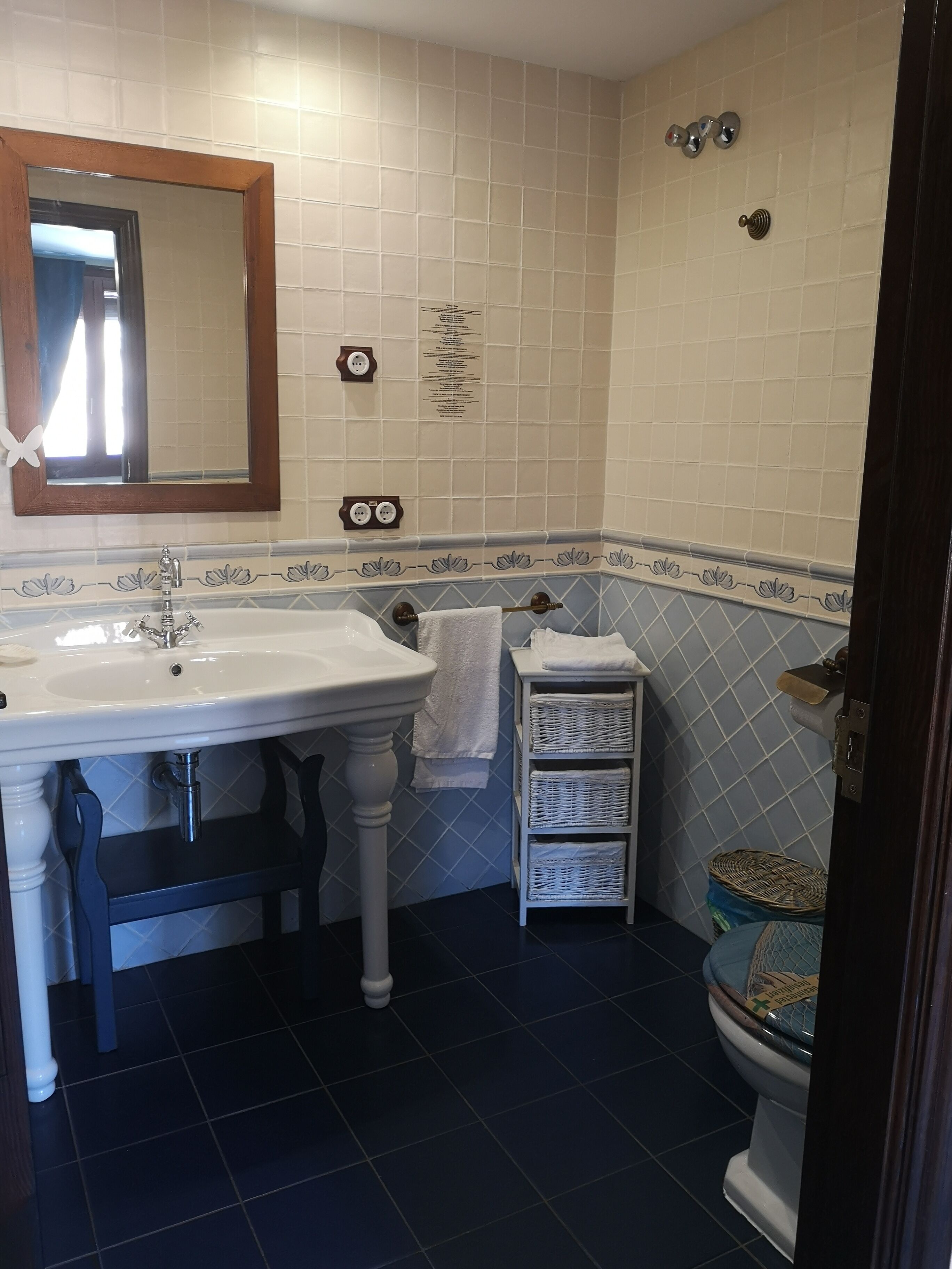 Un baño con un lavabo blanco, un espejo, un inodoro y un estante pequeño con toallas.