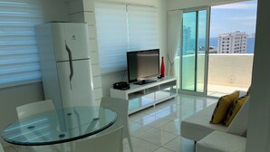 A modern living room with a glass table, white furniture, a flat-screen TV, and a balcony with a city view. - My Rio Penthouse Ipanema Beach (Rio de Janeiro)