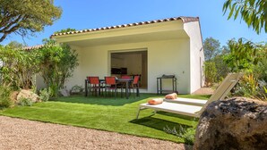 A modern house with a patio, a dining area with red chairs, and a lounge chair. - Les Pins de Santa Giulia (Porto-Vecchio)
