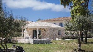 A stone house with a tiled roof, surrounded by trees and a grassy area. - L'Albitru (Bonifacio)