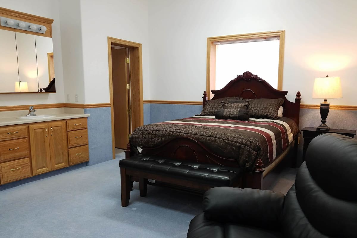 Un dormitorio con una cama de madera, una mesita de noche, una lámpara, un espejo y un aparador de madera.