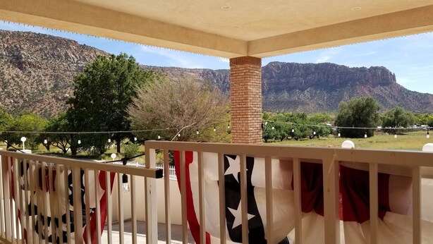 A balcony with a view of a mountainous landscape, a brick pillar, and a white railing. - Zion's Most Wanted Hotel (Hildale)
