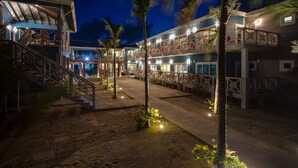 A multi-story hotel with outdoor seating areas and palm trees. - Brisa Oceano Resort (Placencia)