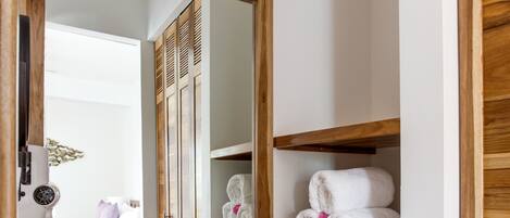Un baño con tocador de madera, un espejo grande y una estantería con toallas.