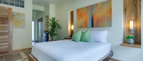 Un dormitorio moderno con una cama grande, una planta en maceta y un cuadro abstracto colorido.