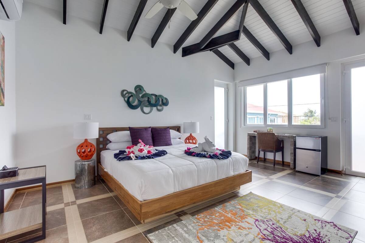 A modern bedroom with a wooden bed, a desk, and a large window.