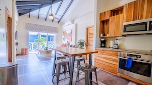 A kitchen with wooden cabinets, a stainless steel oven, and a bar stool area. - Brisa Oceano Resort (Placencia)