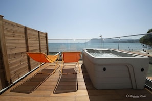 A wooden deck with two orange chairs and a hot tub. - Hotel George Sand (La Seyne-sur-Mer)