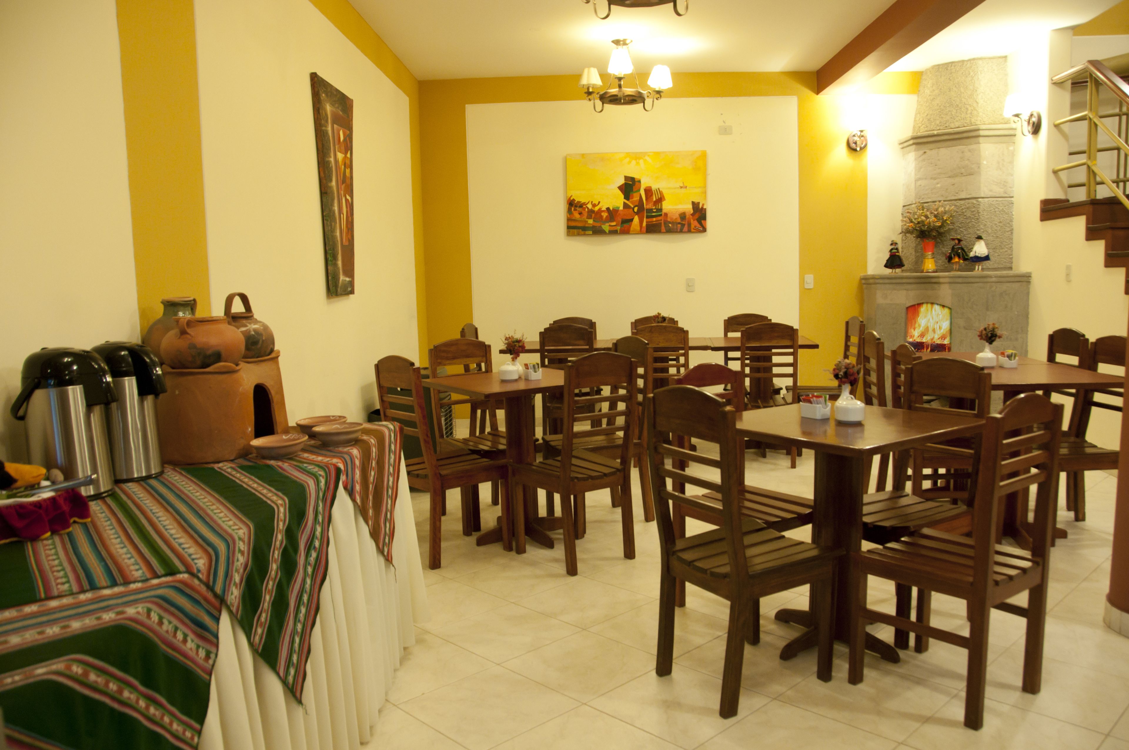A dining area with multiple wooden tables and chairs, a fireplace, and a painting on the wall.