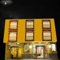 Un edificio amarillo con varios balcones y una entrada protegida por una reja.