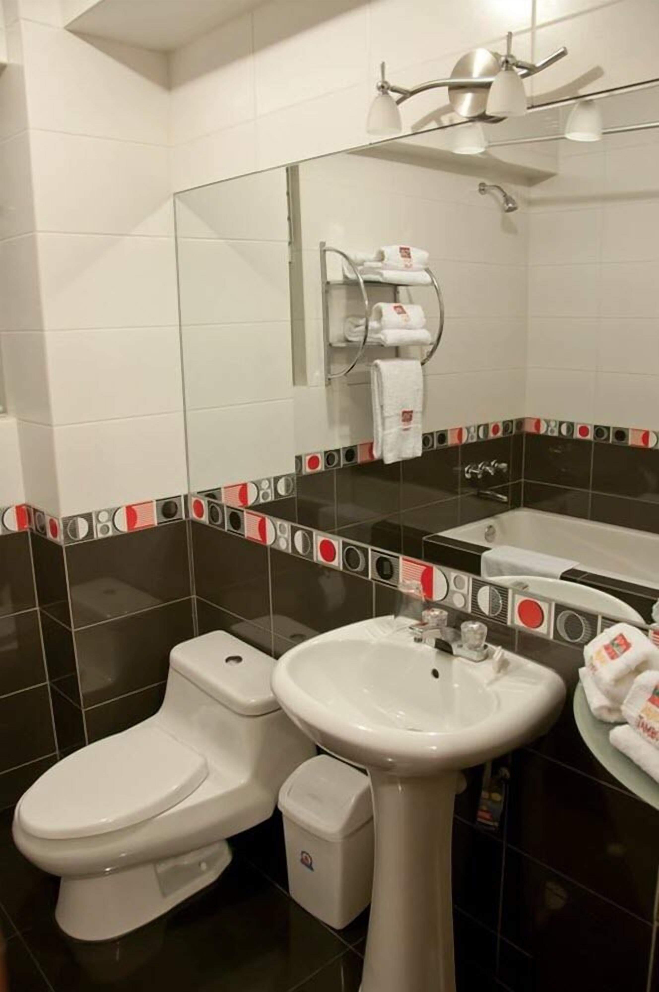 Un baño con inodoro, lavabo, bidé y espejo.