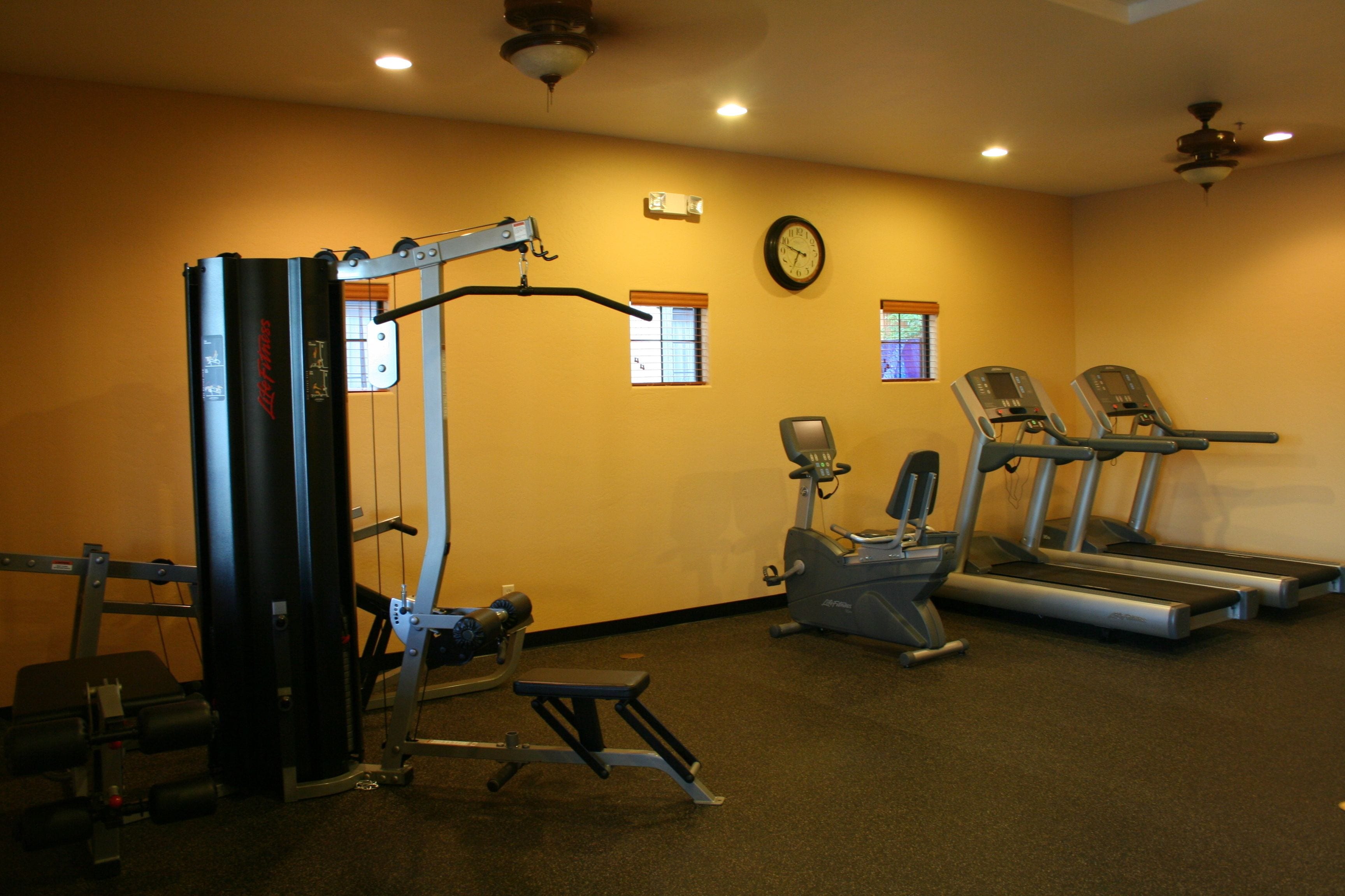 A gym with exercise equipment, treadmills, and a clock on the wall.