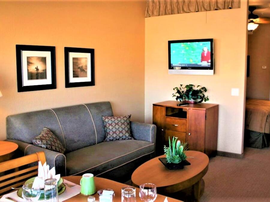 A hotel room with a sofa, a coffee table, a TV, and framed pictures on the wall.