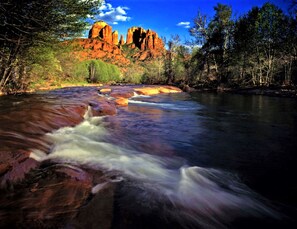 A river flowing through a forest with rocky outcrops and a clear blue sky. - Highlands Resort at Verde Ridge (Cornville)