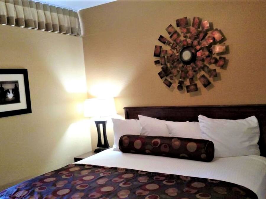 Een hotelkamer met een bed, een ronde wanddecoratie, een ingelijst beeld en een lamp.
