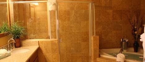 A bathroom with a glass-enclosed shower, a sink with a mirror, and a bathtub.