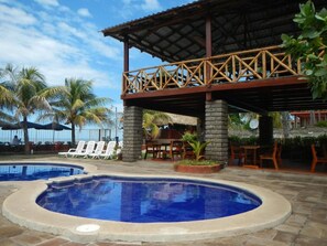 A pool area with lounge chairs and a covered seating area. - Punta Roca Surf Resort (La Libertad)