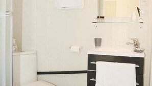 A bathroom with a toilet, a sink, a mirror, and a towel hanging on the wall. - Hôtel L'Oustaou (Le Lavandou)