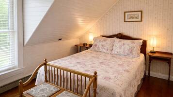 Une chambre avec un plafond en pente, un cadre de lit en bois, une table de chevet et une chaise.