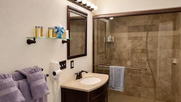 Un baño con ducha de vidrio, lavabo con espejo y toallas.