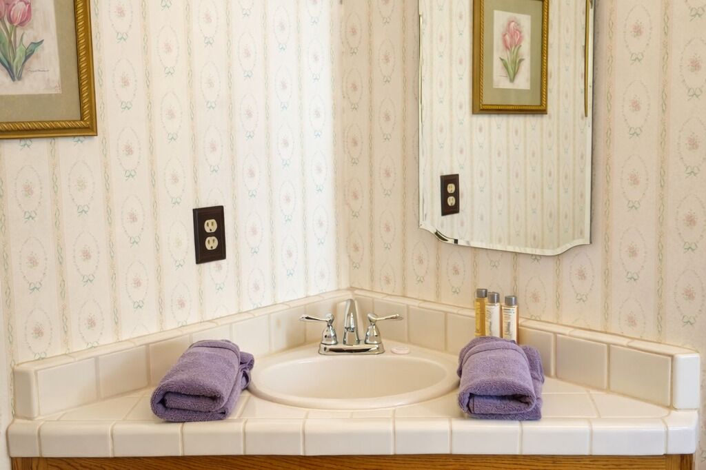 Un baño con lavamanos doble, dos toallas, un espejo y artículos de aseo.