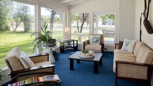 Une véranda avec vue sur l’extérieur, une table basse, un canapé et un fauteuil.