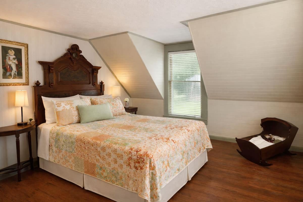 A bedroom with a wooden bed, a nightstand, a chair, and a window with blinds.