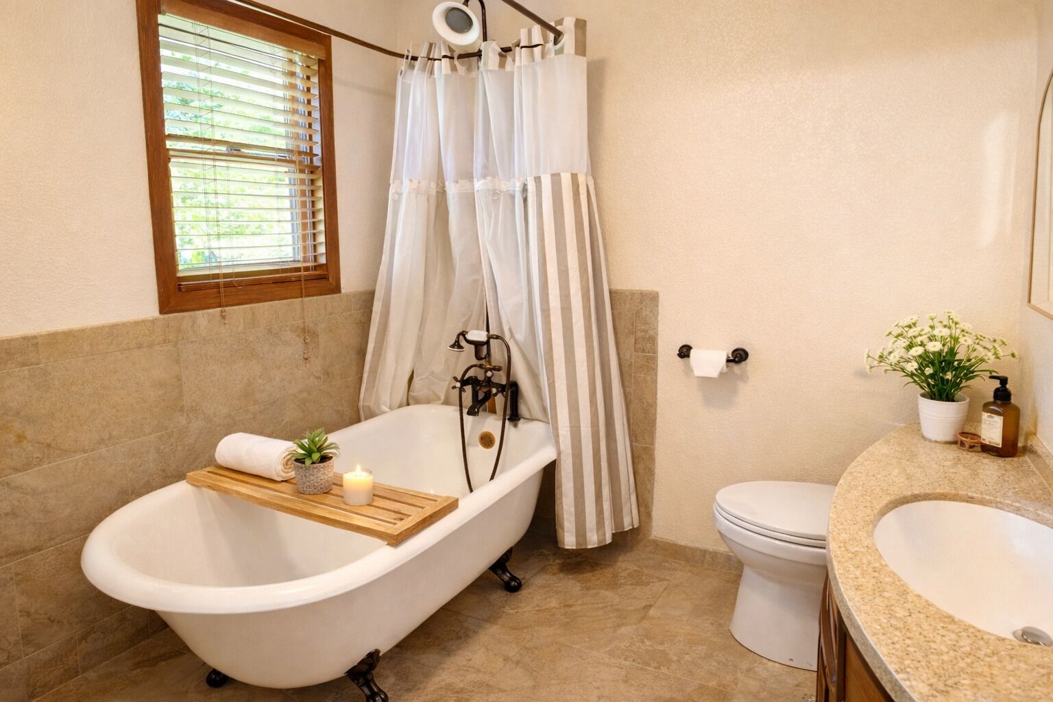 Un baño con bañera independiente, inodoro, lavamanos, ventana con persianas, cortina de ducha y una pequeña planta en maceta.