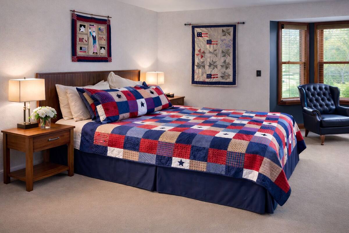 A bedroom with a bed, two nightstands, a chair, and two wall hangings.
