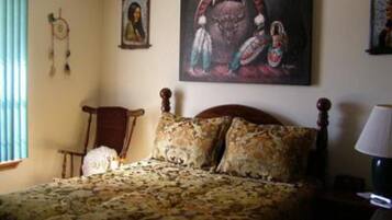 A bedroom with a bed, a chair, a lamp, and a painting on the wall.