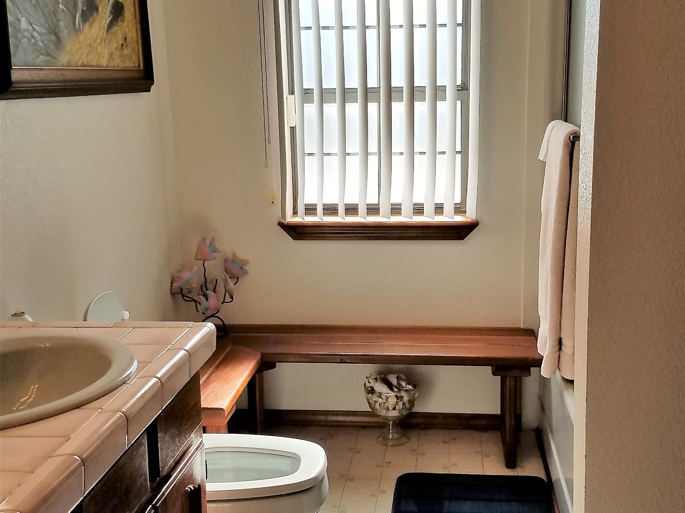 Une petite salle de bain avec des toilettes, un lavabo et un banc.