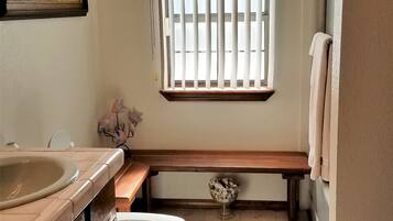 Une petite salle de bain avec des toilettes, un lavabo et un banc.