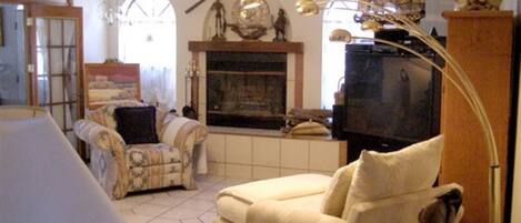 A living room with a fireplace, a television, and a patterned armchair.
