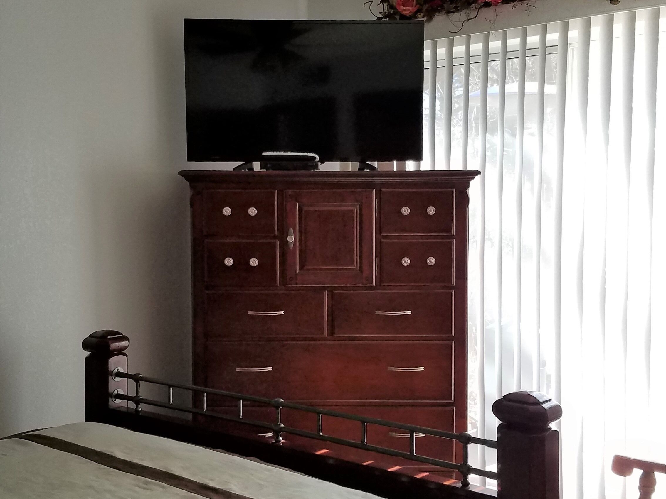 Un aparador de madera con varios cajones y pomos, situado junto a una ventana con persianas.