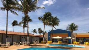 Un área de piscina con diversas opciones de asientos y palmeras.