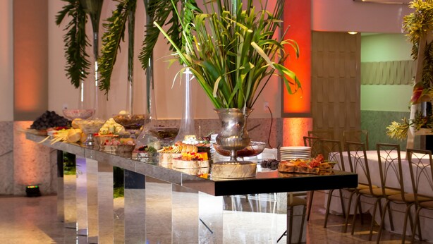 Un área de recepción con mostrador de mármol, plantas en macetas y un diseño de interiores moderno.