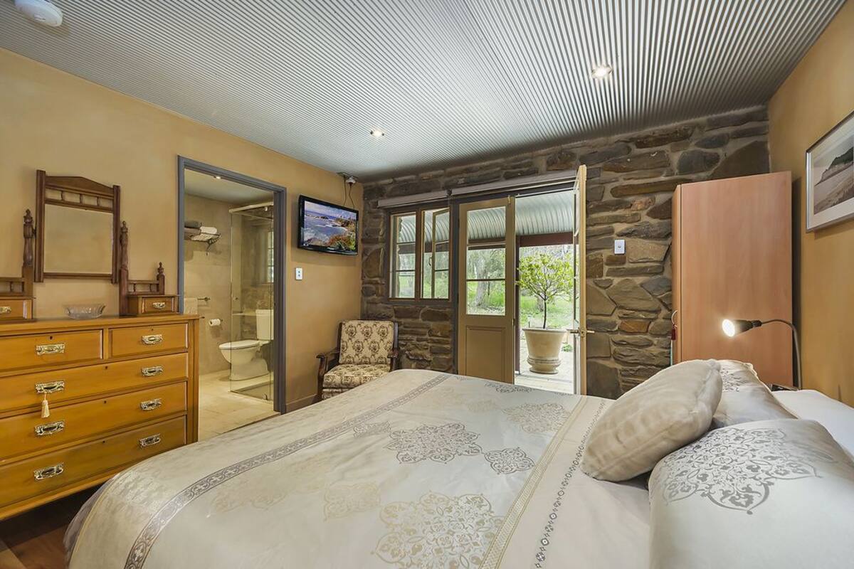 A bedroom with a bed, dresser, and a stone wall.
