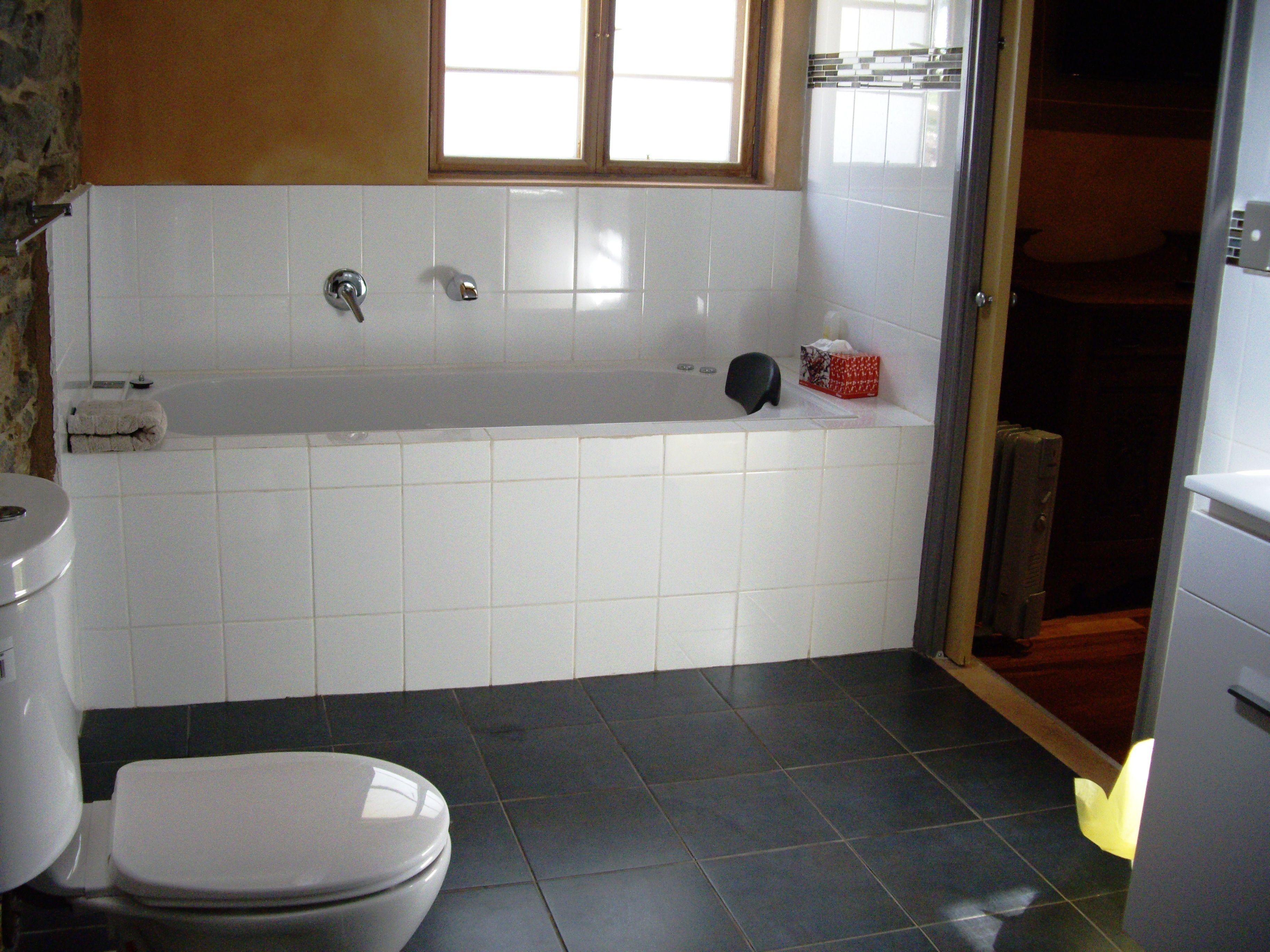 A bathroom with a bathtub, toilet, and a window.