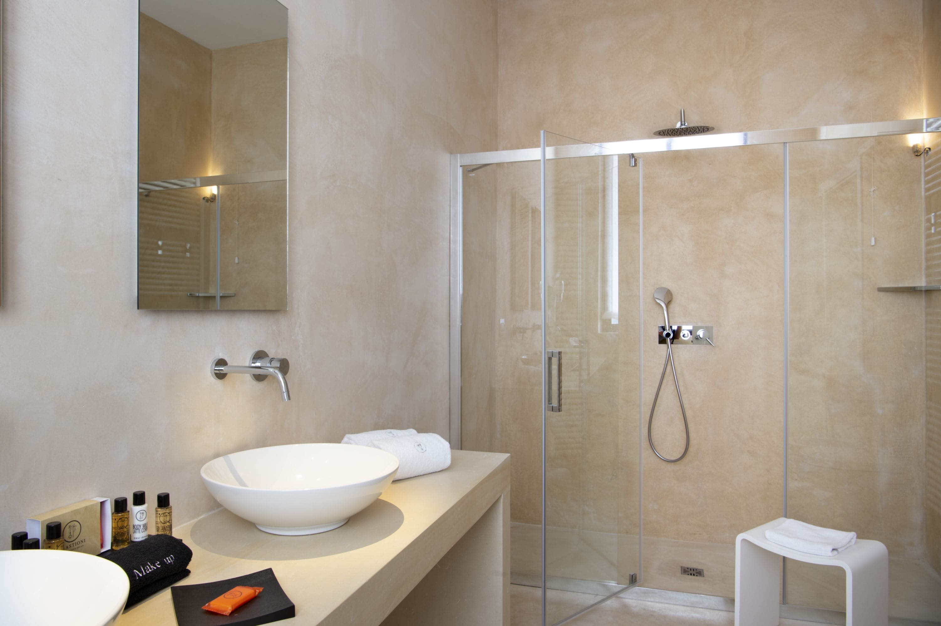 Ein modernes Badezimmer mit einem großen weißen Waschbecken, einer Duschkabine und einem Spiegel über dem Waschbecken.