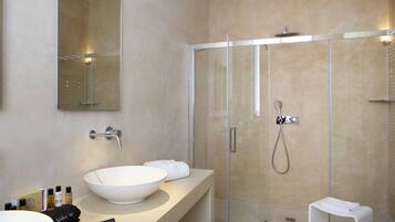Un baño moderno con un lavamanos grande de color blanco, una ducha con cerramiento de vidrio y un espejo sobre el lavamanos.