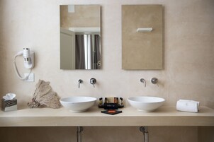 A bathroom with two sinks, a hairdryer, a towel, and a makeup station.