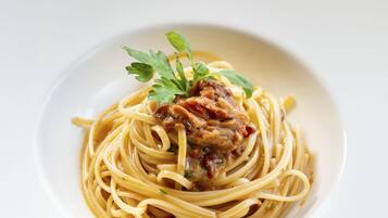 A plate of spaghetti with a meat topping and garnish.