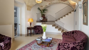 Un salon spacieux avec un escalier, une grande plante et une table basse sur laquelle sont posés des livres.
