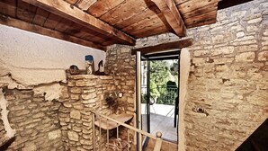 Una habitación rústica con paredes de piedra, techo de madera y una puerta de cristal que da al exterior.