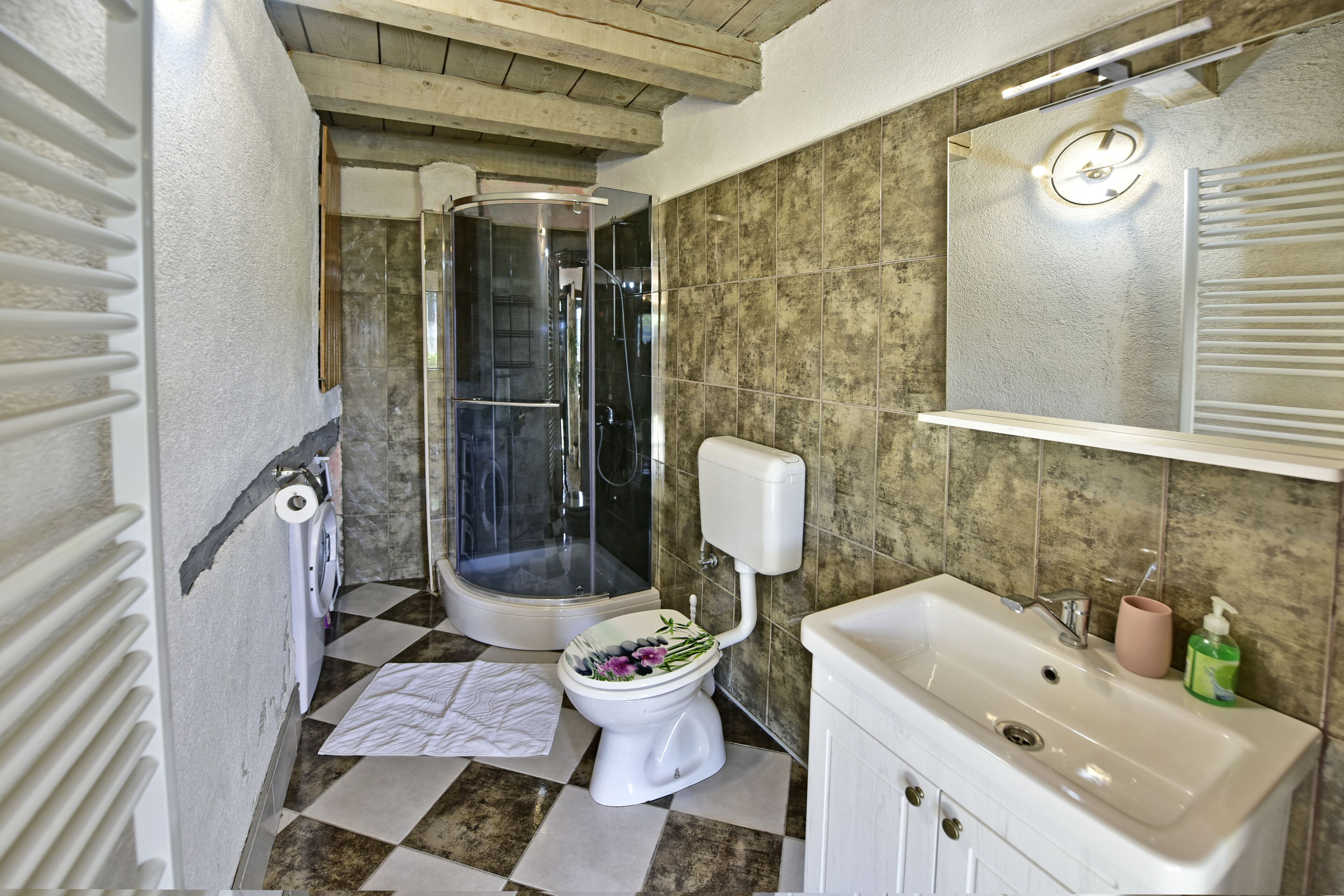 A bathroom with a shower, toilet, sink, and a mirror.