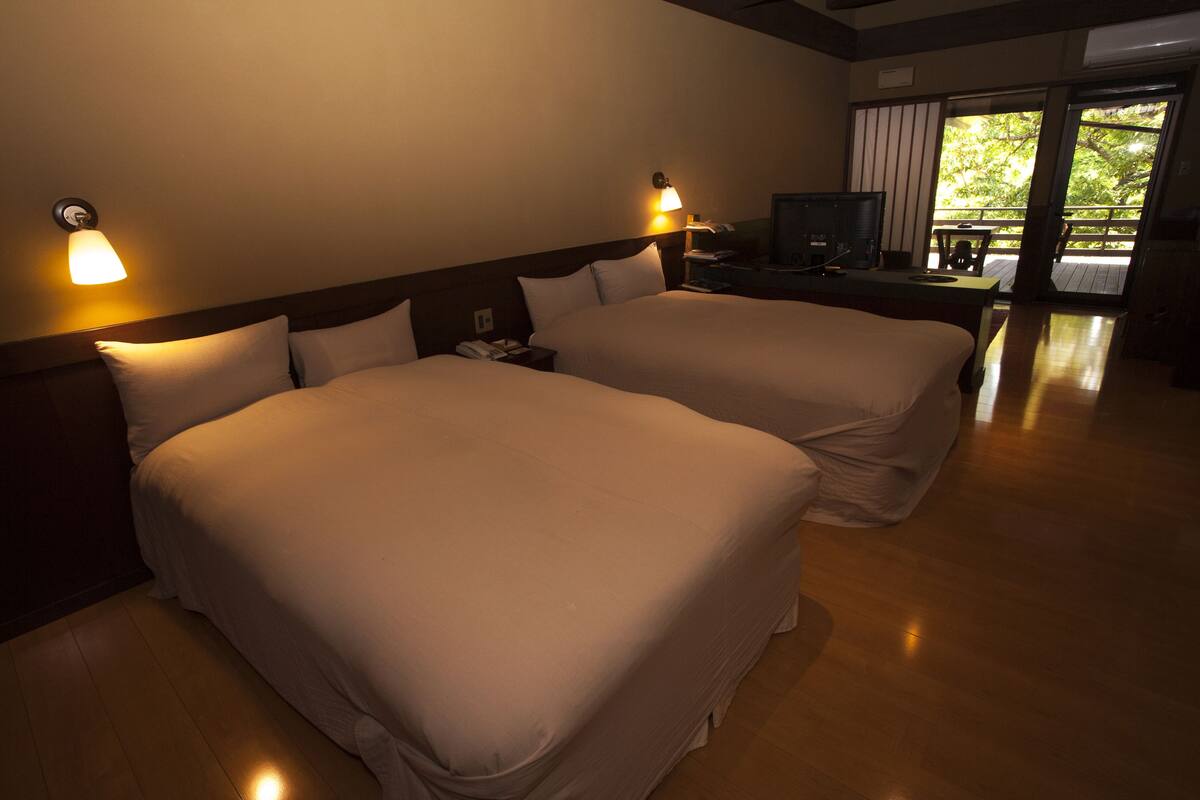 A hotel room with two beds, a television, and a desk with a chair.
